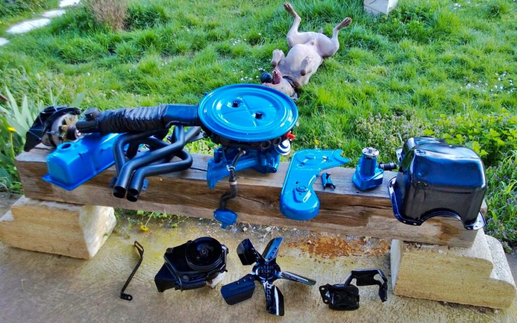 Painted engine parts for 1978 Ford Mustang II restoration, workshop scene with dog in background
