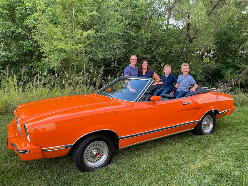 Robert, his wife, and their two sons gathered around the Mustang II Classic II convertible.