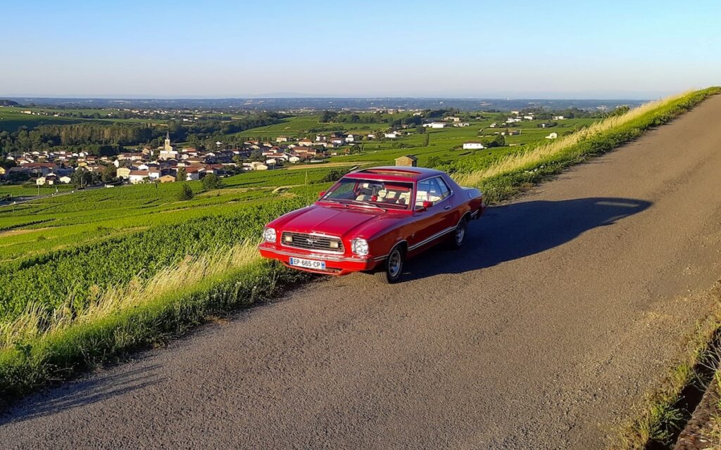 1976 Mustang II parked in the hills of Beaujolais, France, highlighting the classic American car in a scenic landscape.