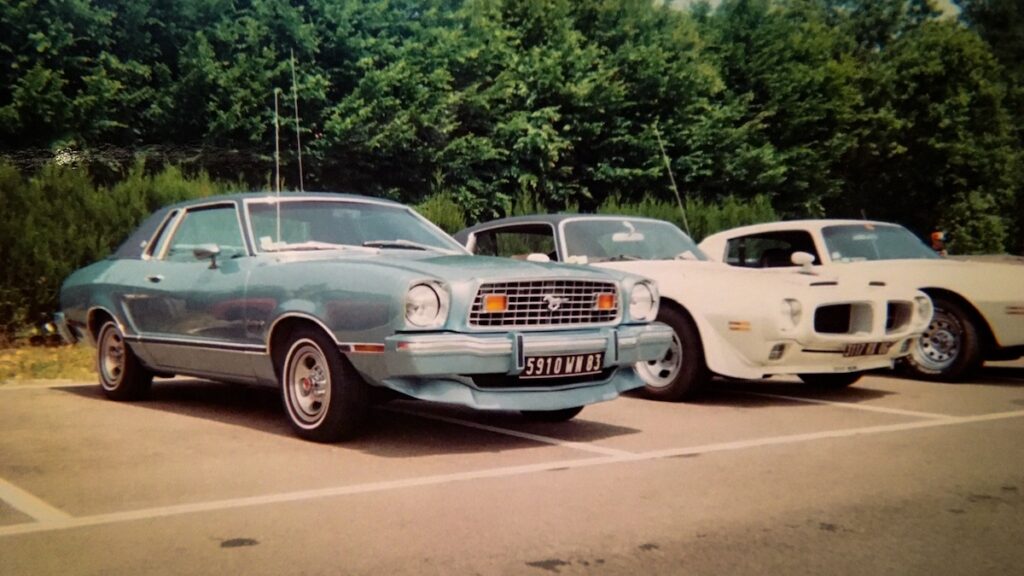 1976 Mustang II Ghia parked among other classic American cars at a car meet in France.