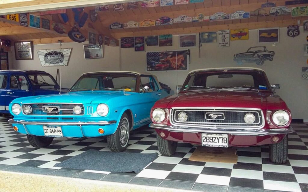 1968 Mustang convertible parked next to a 1966 Mustang in a private garage