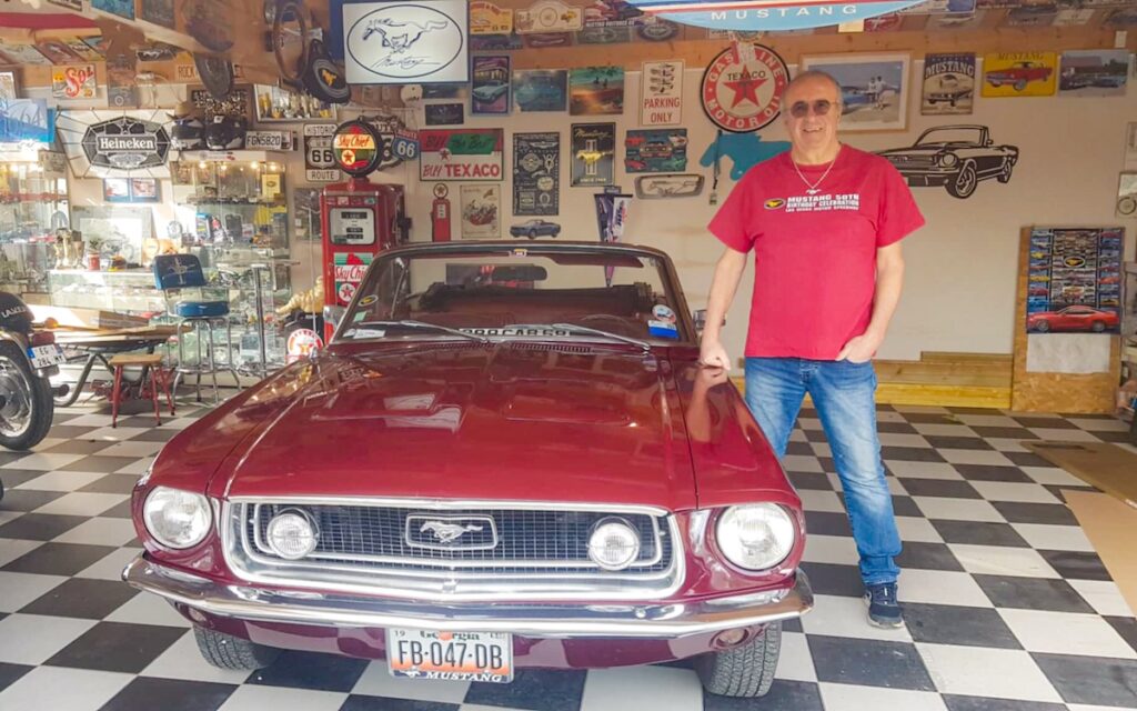 Owner standing next to his 1968 Ford Mustang convertible in his garage