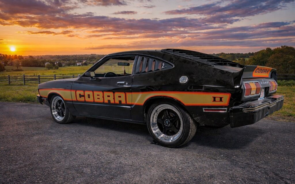 Mustang II Cobra II parked at sunset in a rural landscape