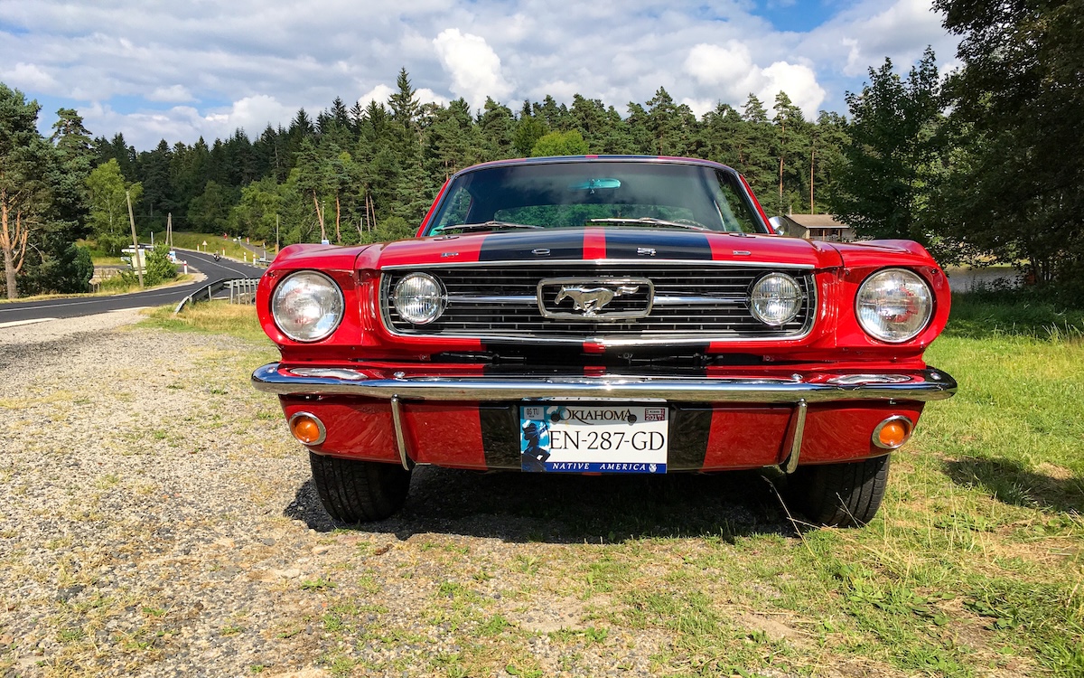 Chloe’s restored 1966 Ford Mustang driving on a quiet road in Auvergne, France.