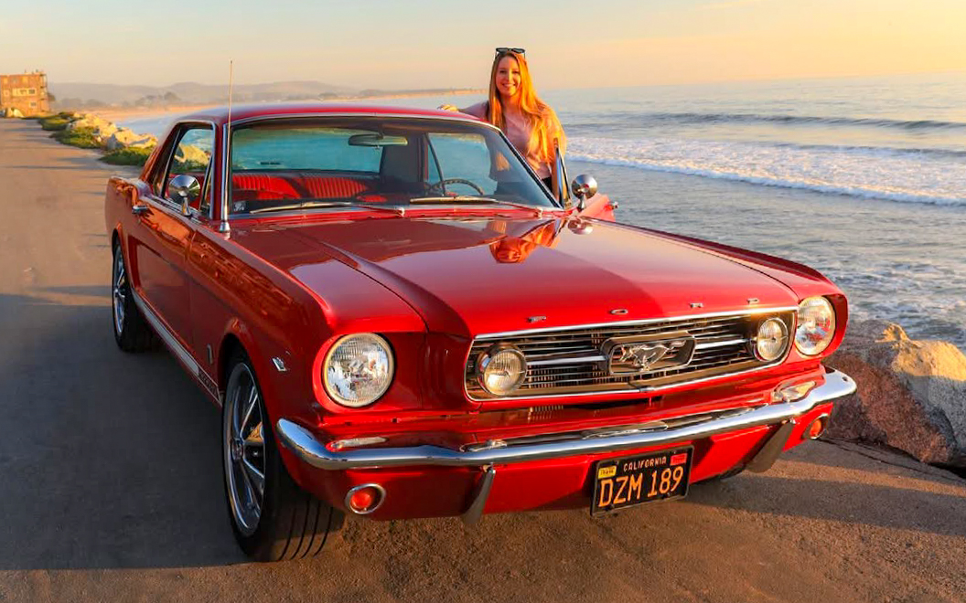 Francesca with her 1966 Ford Mustang coupe parked by the Pacific Ocean in California