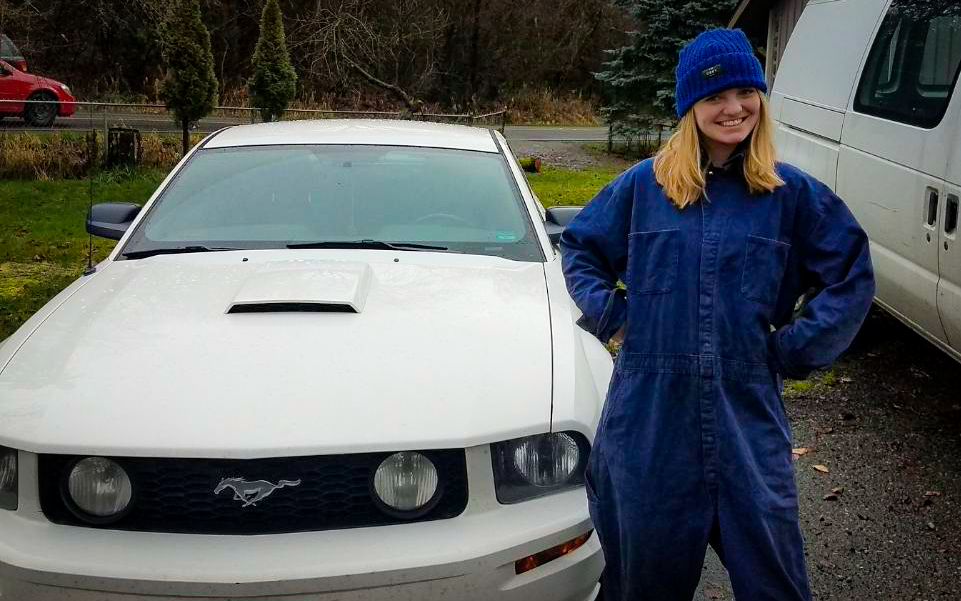 Brittley in her work coveralls beside Jane, the 2005 Mustang GT that taught her not only about cars, but also what she was capable of learning and doing.