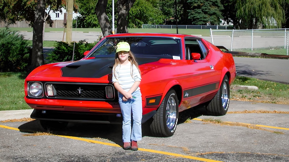 Heather as a child beside the 1973 Mach 1 with newly installed Magnum 500 wheels in 2003